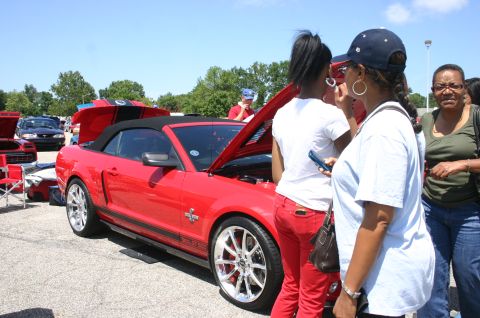 1968 Shelby GT500 - People gather around a red convertible Mustang at an outdoor car show.