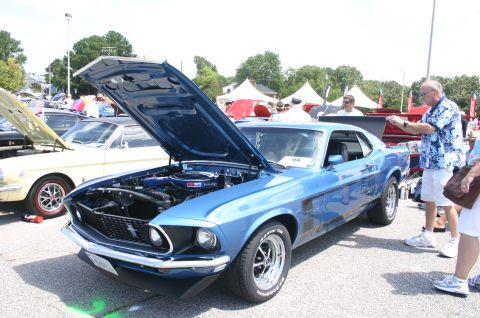 1968 Shelby GT500 - A blue 1969 Ford Mustang Boss 302 is displayed with its hood open at a car show.