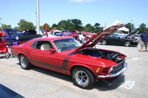 1968 Shelby GT500 - A red 1970 Ford Mustang Boss 302 is displayed with its hood open at a car show.