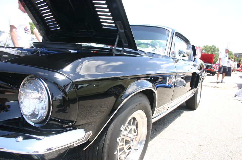 Black classic car with hood open, showing side profile and front wheel. Text on side reads 'GT500'