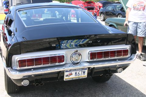 1968 Shelby GT500 - Rear view of a black 1968 Shelby GT500 at a car show, with other vehicles in the background.