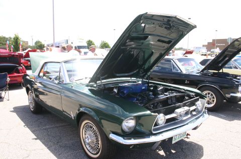1968 Shelby GT500 - A green 1967 Ford Mustang convertible is displayed with its hood up at an outdoor car show.