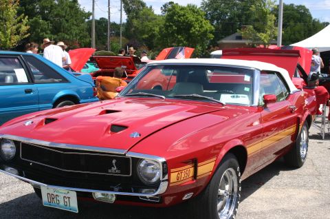 1968 Shelby GT500 - A red convertible with yellow side stripes and GT350 badging is parked at a car show.