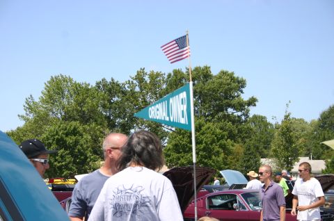 1968 Shelby GT500 - A 1968 Shelby GT500 is displayed at a car show, with attendees and an American flag visible.