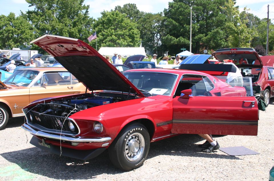 Red 1969 Mustang Mach 1 with hood and door open at a car show