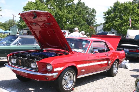 1968 Shelby GT500 - A red 1967 Ford Mustang coupe is displayed with its hood and trunk open at an outdoor car show.