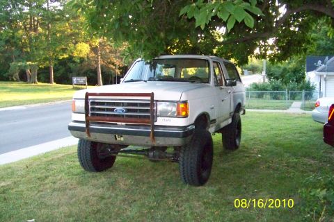 1989 Ford Bronco - This lifted 1987 Ford Bronco is parked on a grassy lawn under a tree.