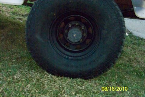 1989 Ford Bronco - Close-up of a vehicle's tire and black steel wheel on grass.