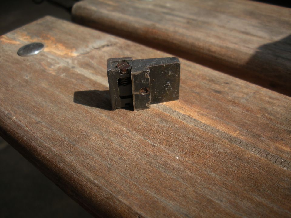 Metal part with spring mechanism on wooden surface