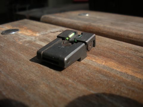 1996 Ford Bronco - Close-up of a gun sight with tritium inserts resting on a wooden surface.
