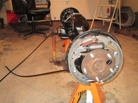 1979 Ford Bronco - The rear axle assembly, likely from a truck or SUV, is supported by orange jack stands in a garage setting.