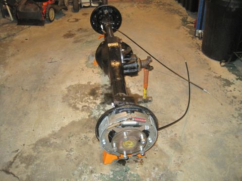 1979 Ford Bronco - A black rear axle assembly with drum brakes is shown on orange stands in a garage.