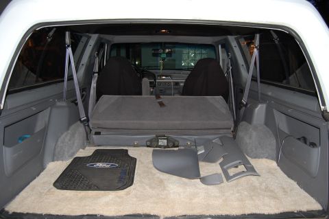 1994 Ford Bronco - The cargo area of a 1994 Ford Bronco shows its folded rear seat, floor mats, and interior trim pieces.
