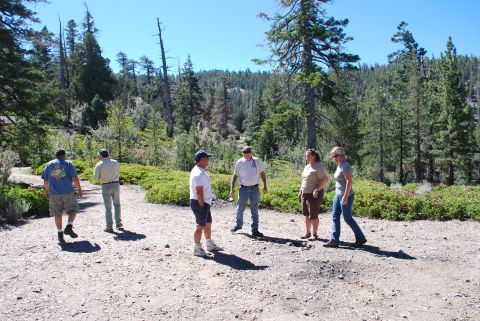 1996 Ford Bronco - A group of people gather on a dirt path in a wooded area on a sunny day.