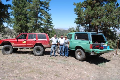 1996 Ford Bronco - Three people pose with a green 1996 Ford Bronco and a red Jeep Cherokee during an off-road excursion.