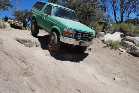 1996 Ford Bronco - 1996 Ford Bronco navigating a challenging off-road course with another vehicle in the background.