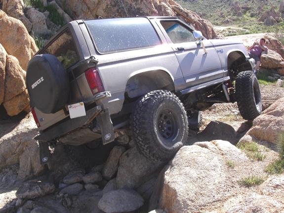 Tan Bronco II with Bronco II spare cover climbing between granite boulders