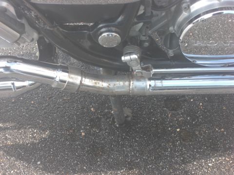 1986 Honda Shadow Aero - Close-up of a motorcycle's chrome exhaust pipe and engine cover, showing some rust on the pipe.