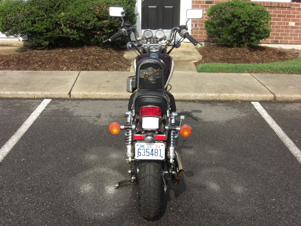 Motorcycle rear view, dark purple and white, with a license plate reading 635481