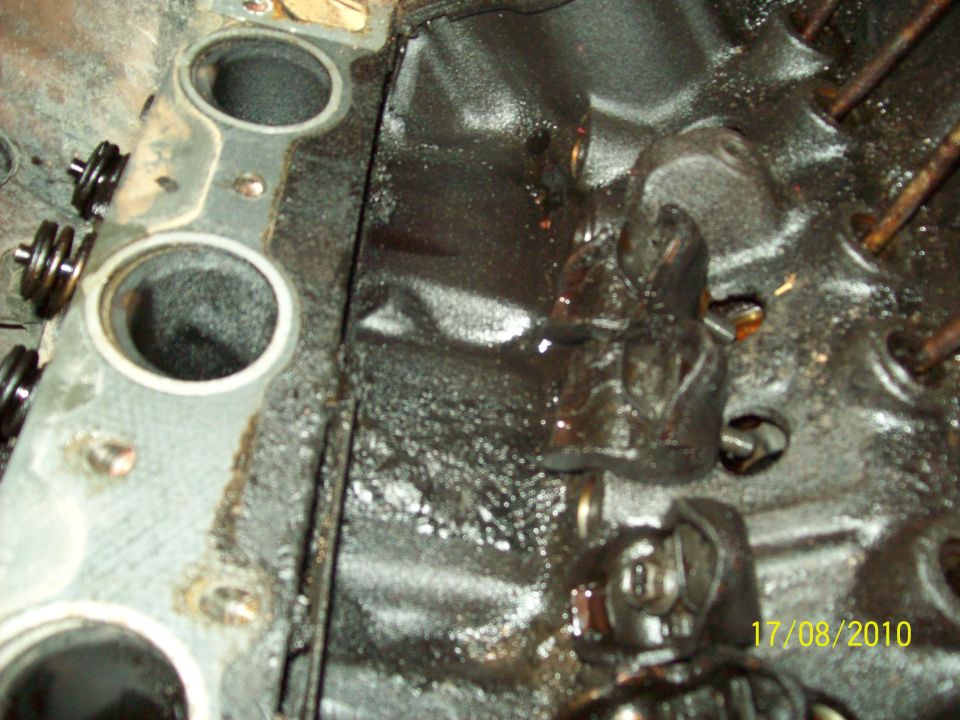 Close-up of an engine block showing valve springs and lifters, covered in oil