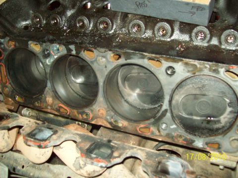 1985 Ford Bronco - Close-up view of an engine block's cylinder head mating surface, revealing pistons and cylinder bores.
