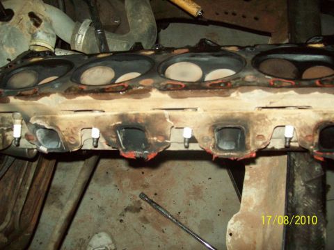 1985 Ford Bronco - Close-up of an engine's cylinder head, revealing exhaust ports and spark plug mounts.