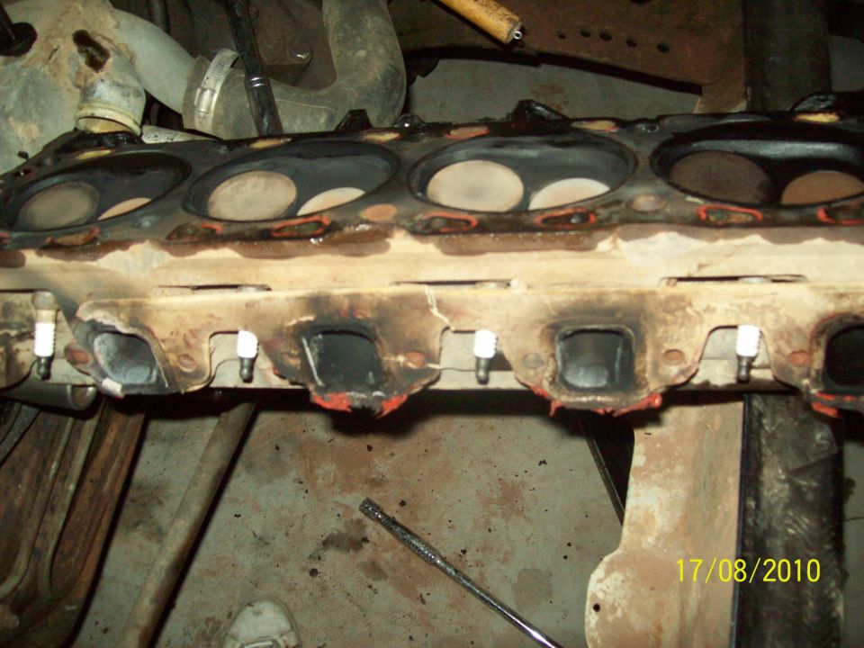 Engine cylinder head with spark plugs installed, showing exhaust ports