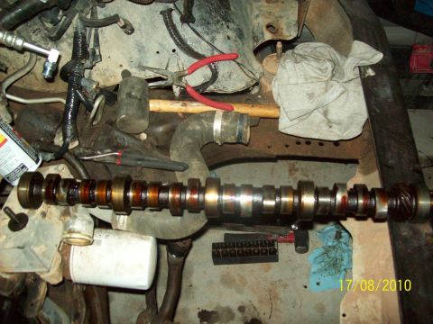 1985 Ford Bronco - A camshaft lies disassembled from an engine, surrounded by tools and engine components.