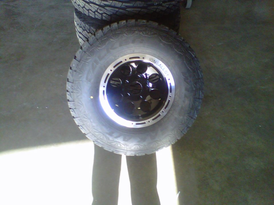 Tire and black ION Alloy wheel with silver trim, stacked on other tires