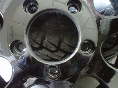 1994 Ford F-150 - A close-up view of a shiny black truck wheel reveals the tread pattern of the tire mounted within.