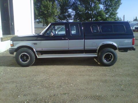 1994 Ford F-150 - Side view of a two-tone 1994 Ford F-150 pickup truck equipped with a camper shell.