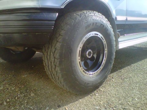 1994 Ford F-150 - A close-up shot focuses on the aggressive tread of a truck's off-road tire and its custom ION ALLOY wheel.