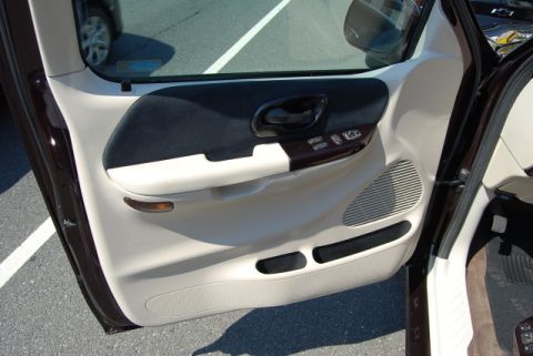 2007 Ford Mustang - The interior of a car door is visible, showing beige and dark fabric panels with wood trim accents.