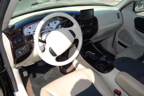2007 Ford Mustang - The interior features a white steering wheel, beige upholstery, and wood grain accents on the dashboard and center console.