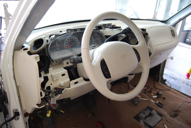 Interior of a 2002 Ford Expedition with dashboard disassembled, showing steering wheel and instrument cluster