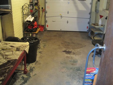 1979 Ford Bronco - Interior view of a cluttered garage with a large overhead door and various storage items.