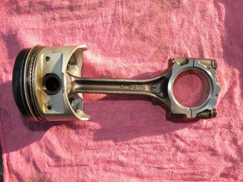 1998 Subaru Legacy - A disassembled engine component, a piston connected to its connecting rod, lies on a pink cloth.
