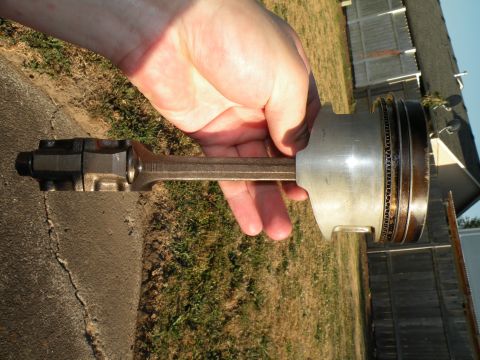 1998 Subaru Legacy - A piston and connecting rod assembly is held for inspection, revealing signs of wear.