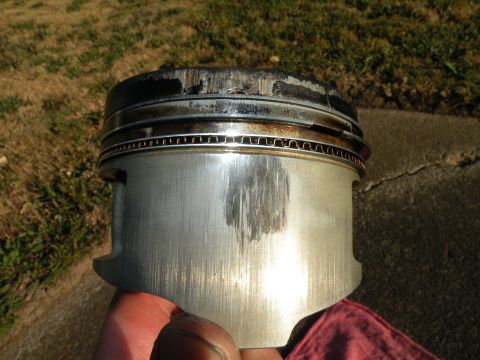 1998 Subaru Legacy - This engine piston shows significant wear and damage to its surface.