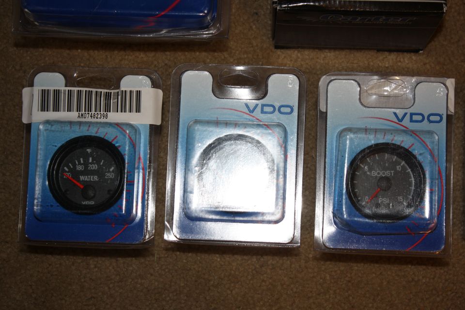 Three VDO automotive gauges in packaging: water temperature, blank, and boost pressure