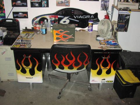 1981 Ford Bronco - A desk and chair decorated with flame decals, surrounded by car memorabilia and office supplies.