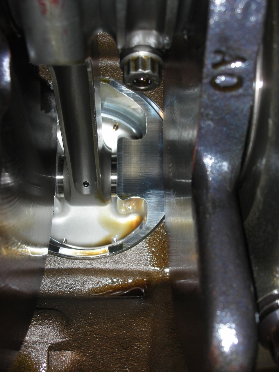 Close-up of engine crankshaft, connecting rod, and piston with oil residue. "AO" visible on metal