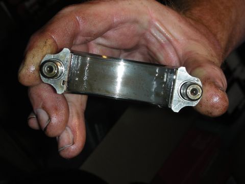 1992 Ford Crown Victoria - A mechanic holds a worn engine bearing, indicating potential internal engine issues.