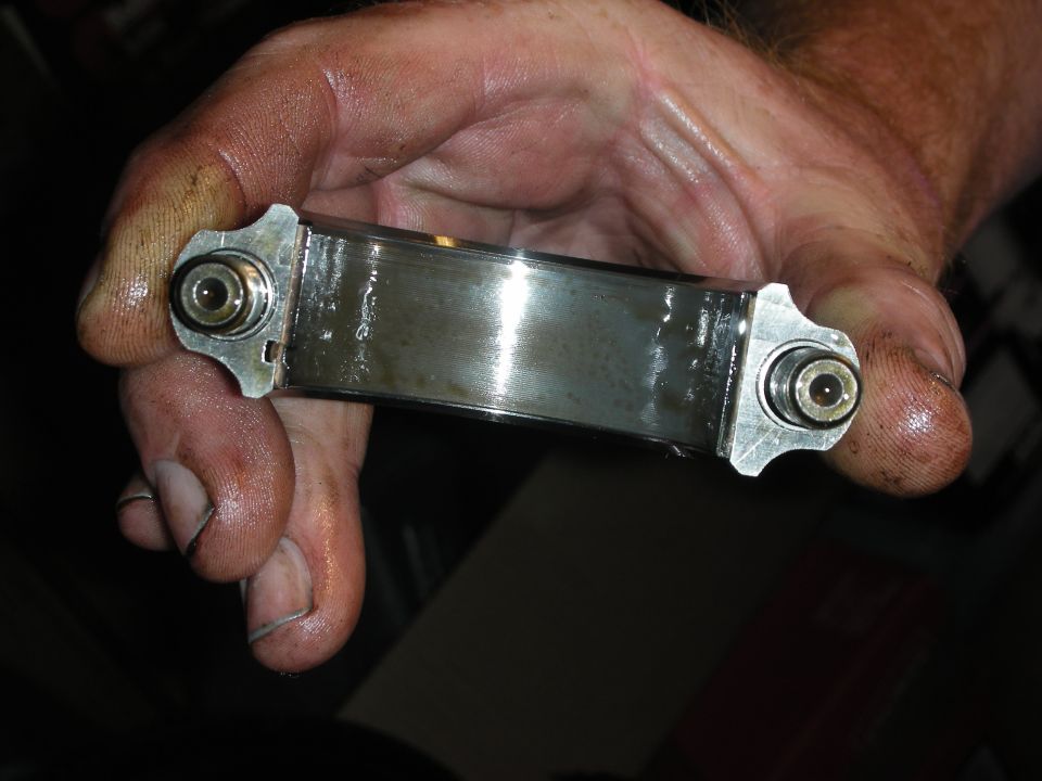Engine bearing with visible wear and oil residue held in a greasy hand
