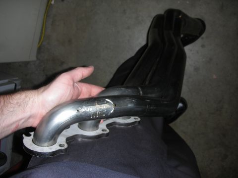 1992 Ford Crown Victoria - Close-up of a set of black exhaust headers, held by a person's hand.