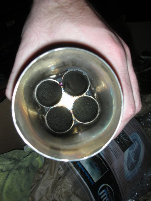 1992 Ford Crown Victoria - Four-tube exhaust header collector, likely for a Ford engine, held in hand with packaging visible.