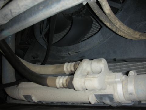 2004 Ford Crown Victoria - Close-up view of hoses and fan shroud in a vehicle's engine bay.