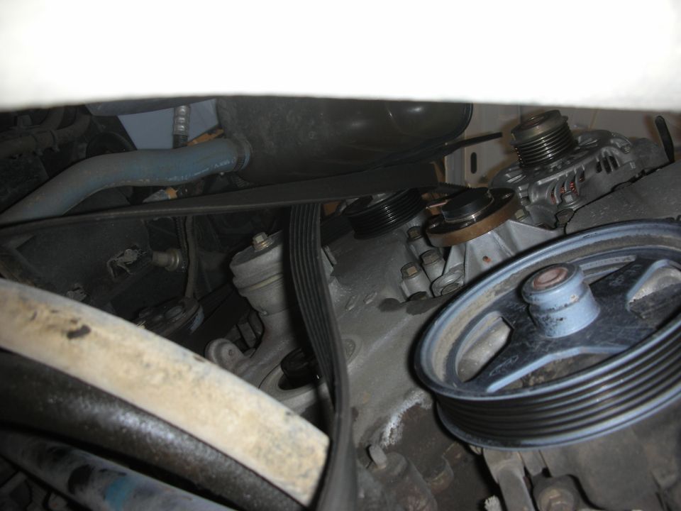 Serpentine belt, power steering and alternator pulleys in a dim engine bay