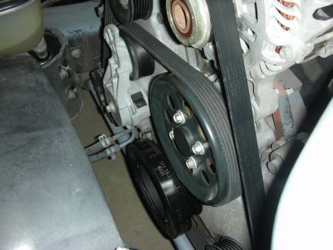 2004 Ford Crown Victoria - Close-up view of engine belt and pulleys, with some text visible on a black pulley.