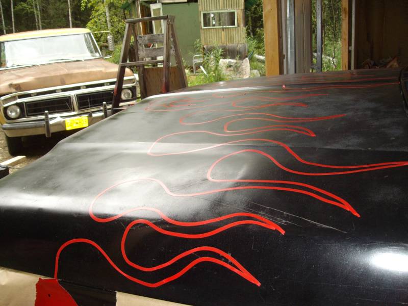 Black hood with red flame decals, showing a portion of a brown truck in the background